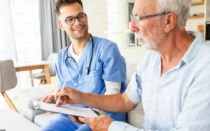 Male nurse talking to seniors patients while being in a home visit.